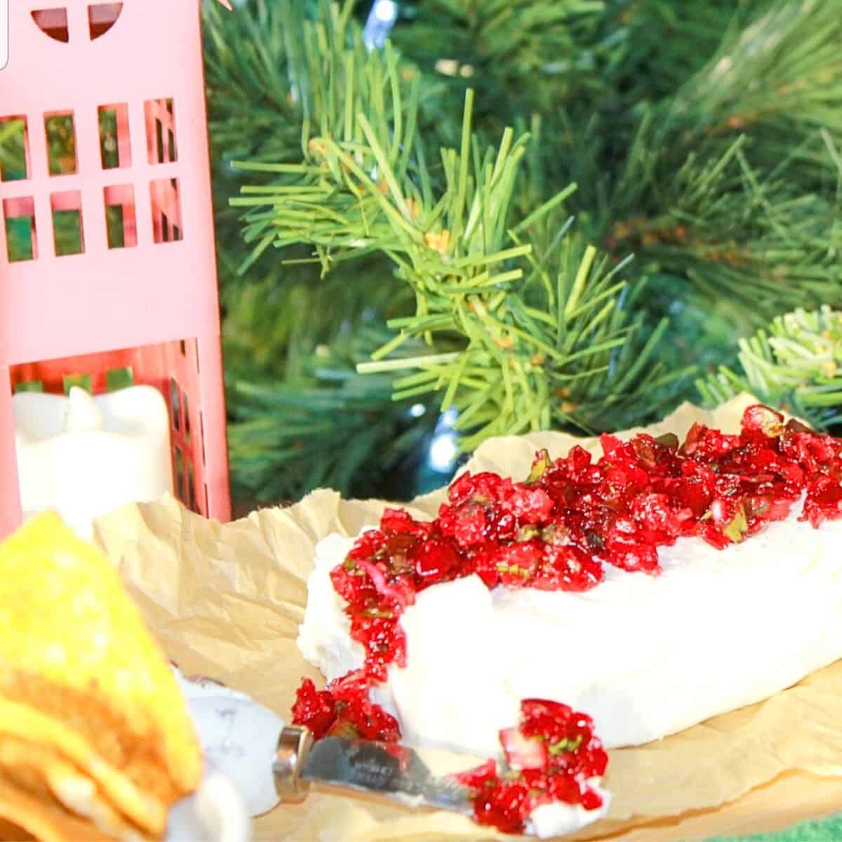 Cranberry jalapeno dip on a tray with a Christmas tree and candle in the background.