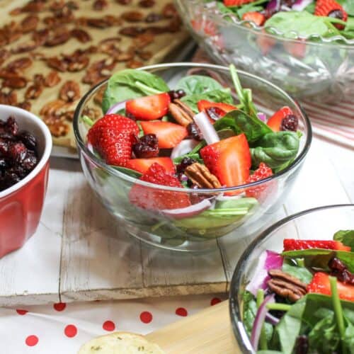 Strawberry spinach salad in a bowl sitting on a farmhouse table.