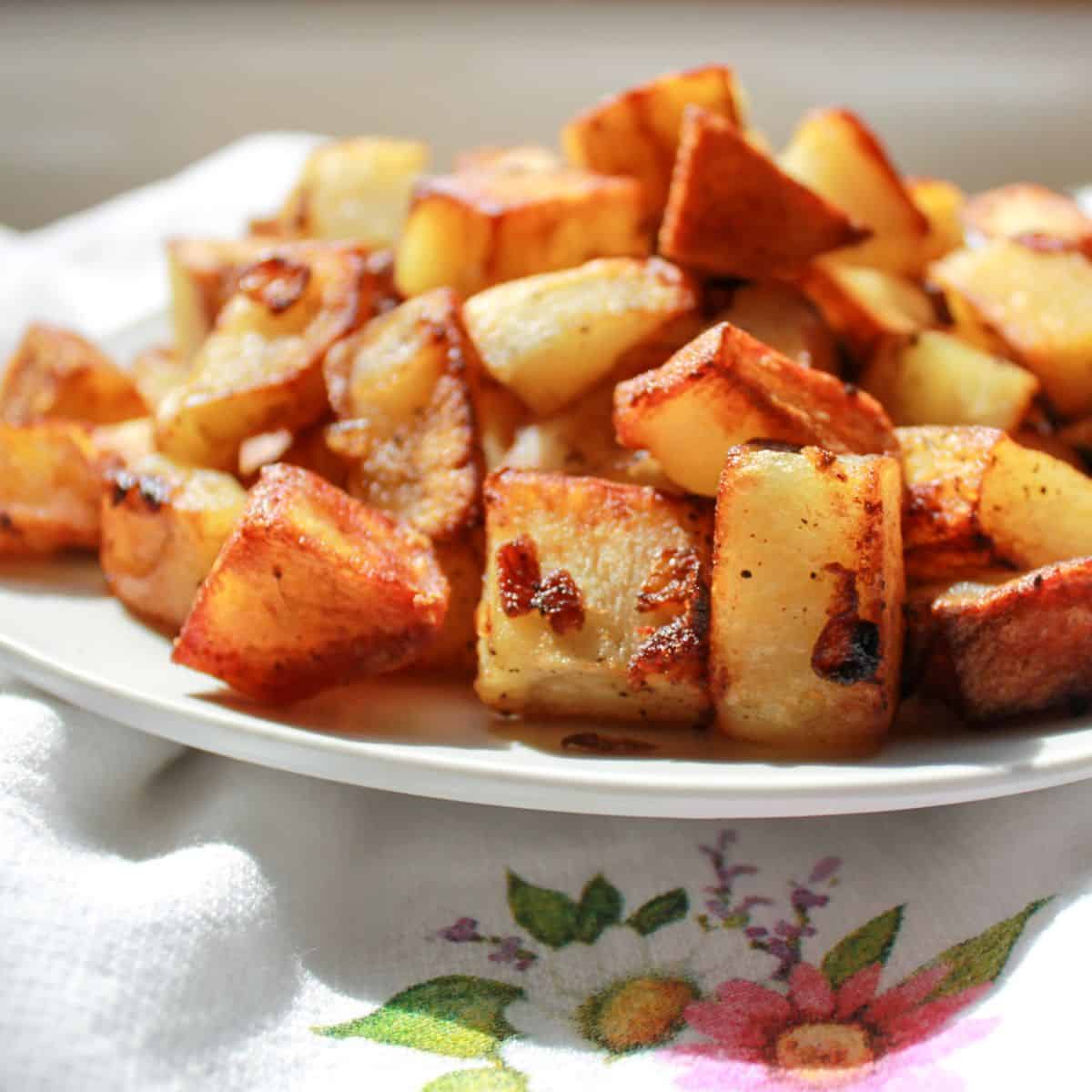 Fried potatoes in a bowl sitting on a dishtowel.