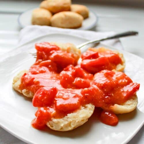 Southern tomato gravy over homemade biscuits. More biscuits sitting on another plate.