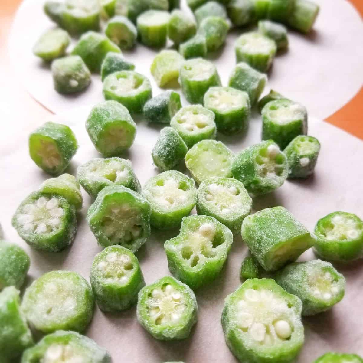 Okra cut up into rounds on a baking sheet.