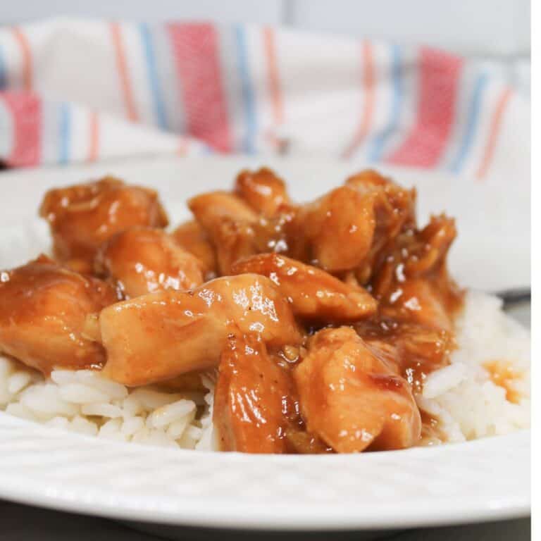 Orange bbq chicken over rice in a white serving bowl.