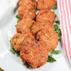 Salmon patties on a white plate with a pink and white stripped towel.