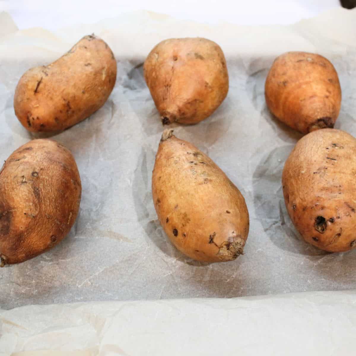 Unbaked sweet potatoes on a baking sheet.