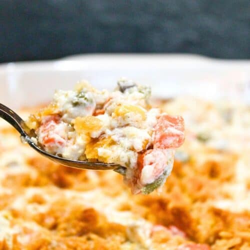Vegetable casserole with a spoon in a white bowl.