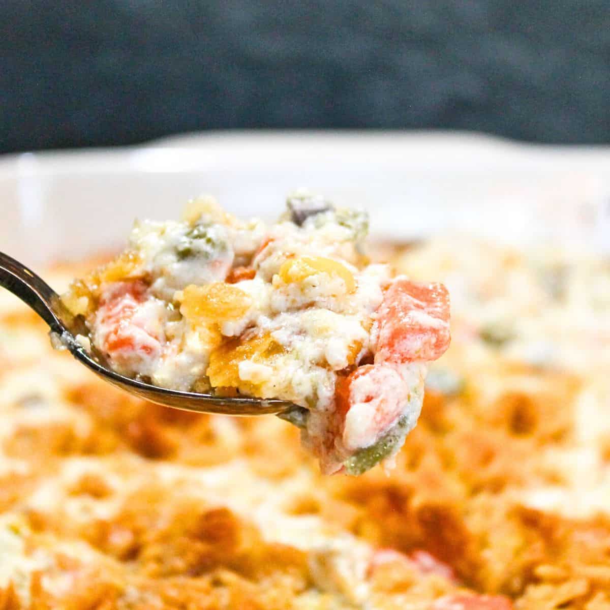 Vegetable casserole with a spoon in a white bowl.
