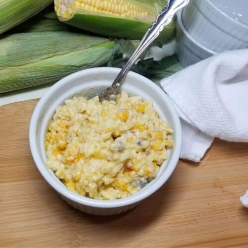 Yellow Rice and corn in a white baking dish with a spoon.