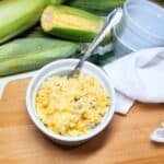 Yellow Rice Corn Casserole in a baking dish with whole corn in background.